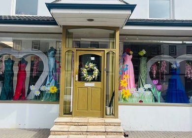 Colorful dresses in Pure Glow's Carlisle, England window display highlighting beauty and fashion.