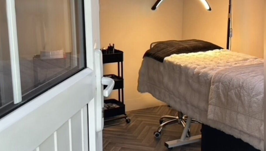 Cozy treatment room at E.N Beauty, Preston, England, GB, featuring a warm-lit massage bed and equipment.