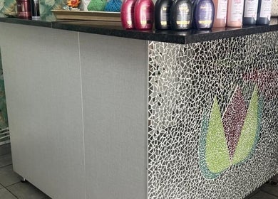 Sleek reception desk at Sheckies Hair, Cape Town, Western Cape, ZA with stylish mosaic design and hair products.
