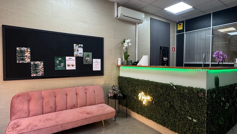 Recepción moderna en Nayco centro estético, Palma, Illes Balears, ES, con sofá rosa y decoración verde.