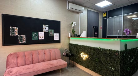 Recepción moderna en Nayco centro estético, Palma, Illes Balears, ES, con sofá rosa y decoración verde.