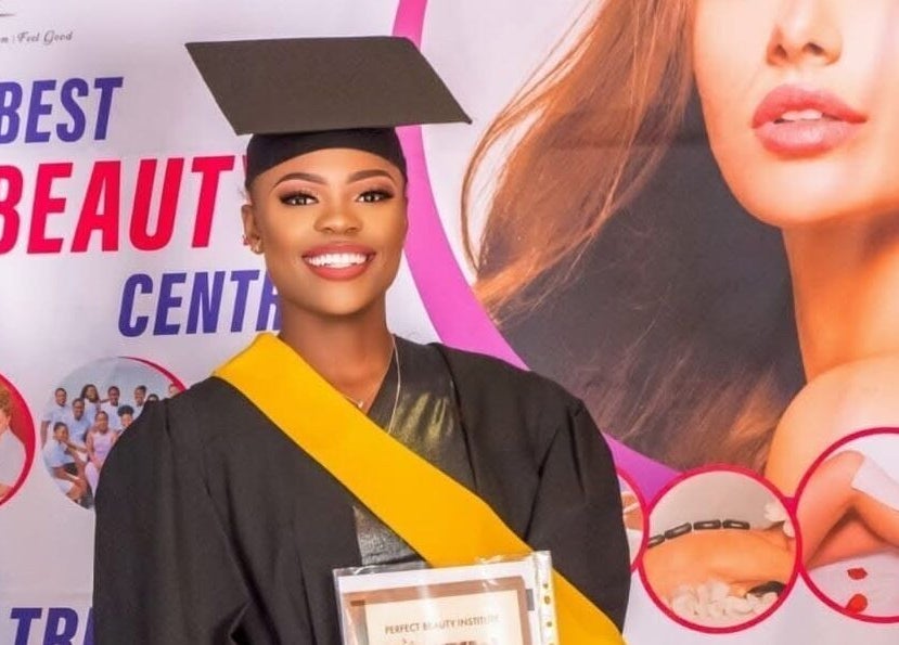A happy graduate holds a certificate in front of a beauty center banner at Bots Massage Mobile, Cape Town, Western Cape, ZA.