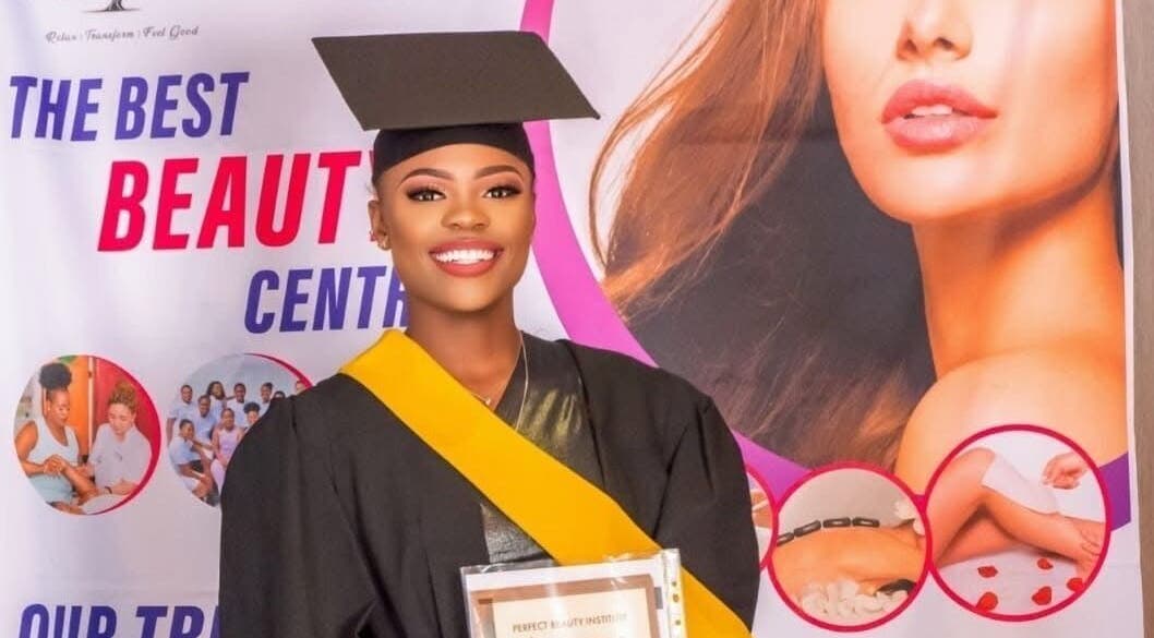 A happy graduate holds a certificate in front of a beauty center banner at Bots Massage Mobile, Cape Town, Western Cape, ZA.