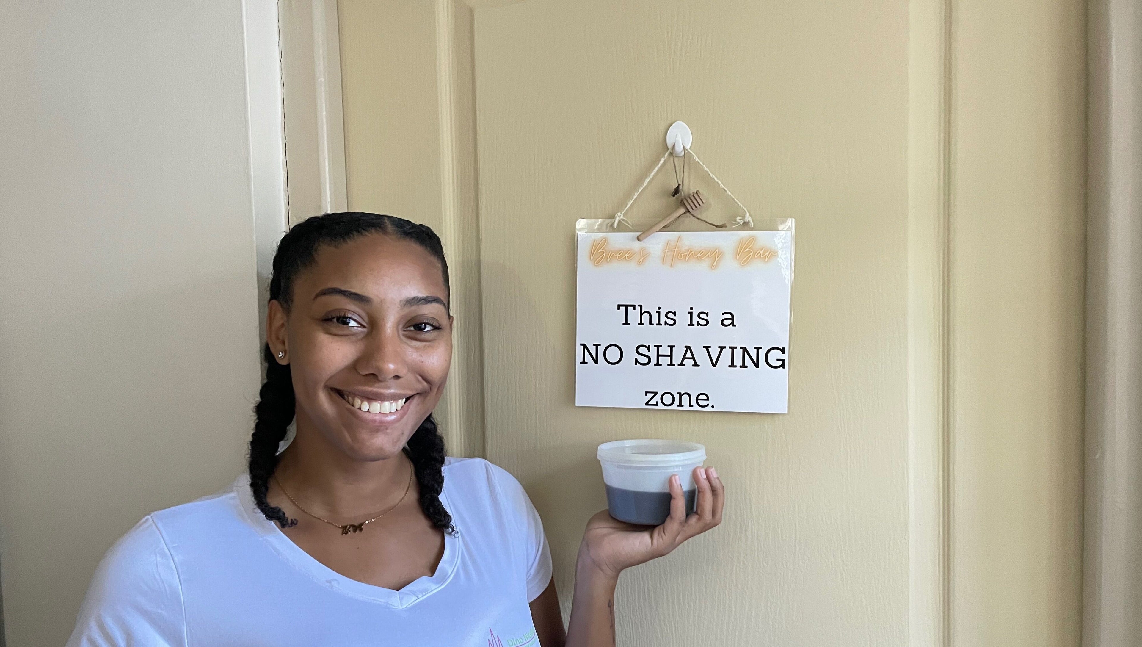 Smiling woman holding honey jar at Bree's Honey Bar CW, Willemstad, Curaçao, CW. Signage: 'No Shaving Zone'.