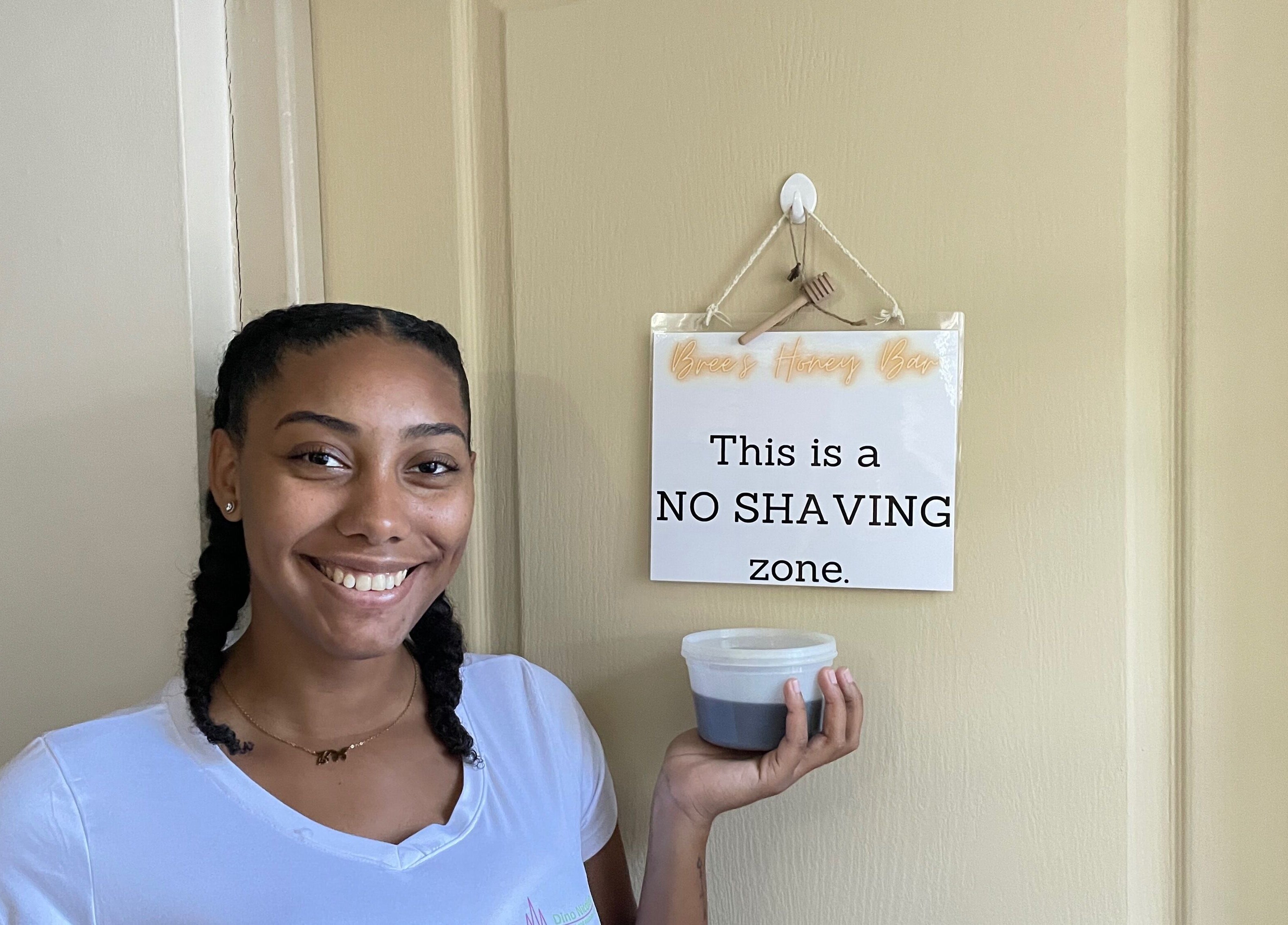 Smiling woman holding honey jar at Bree's Honey Bar CW, Willemstad, Curaçao, CW. Signage: 'No Shaving Zone'.