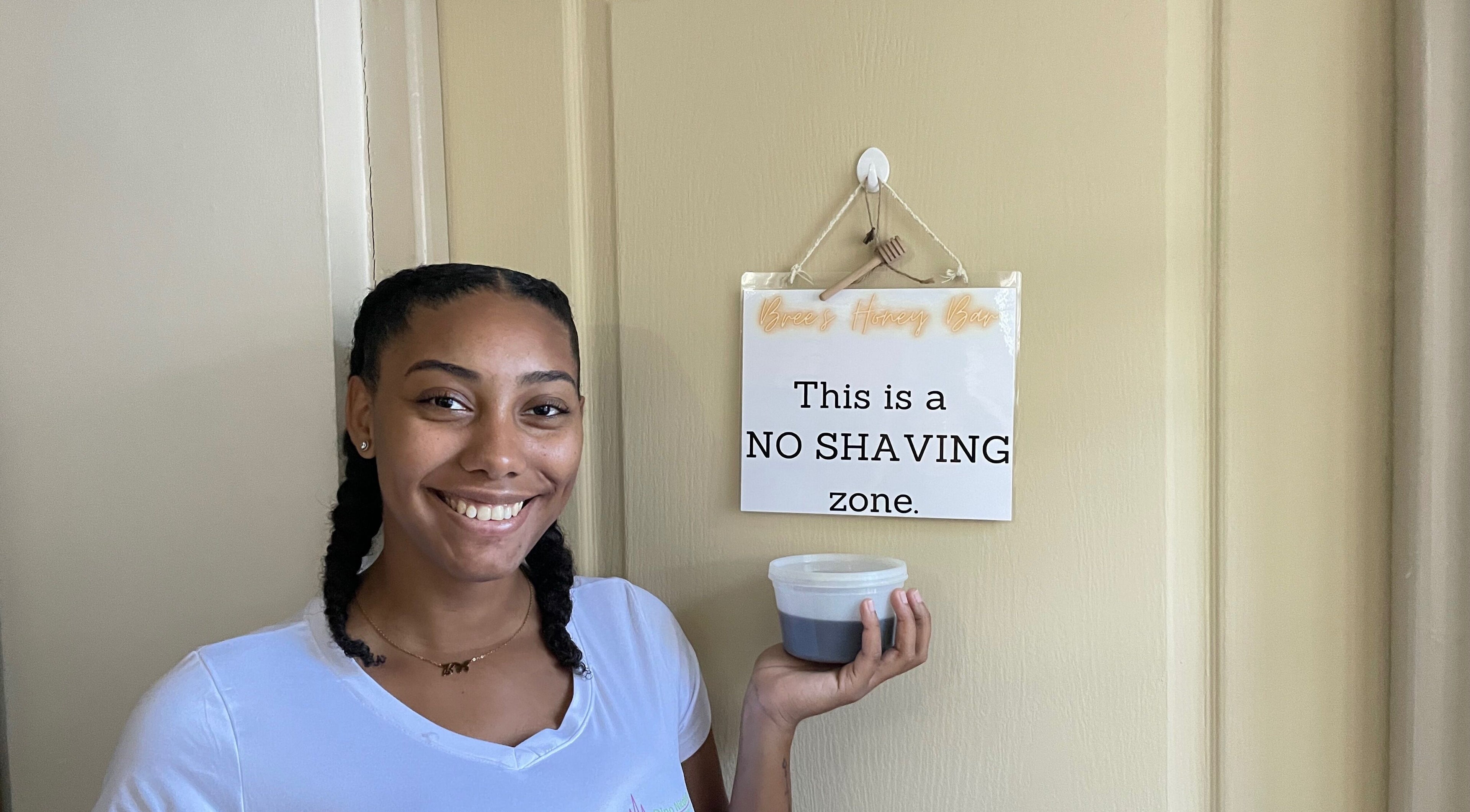 Smiling woman holding honey jar at Bree's Honey Bar CW, Willemstad, Curaçao, CW. Signage: 'No Shaving Zone'.