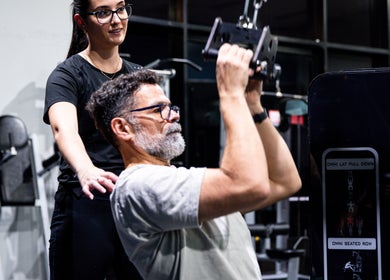 Instructor at LeanFit Performance, Birtinya guides a man using gym equipment.