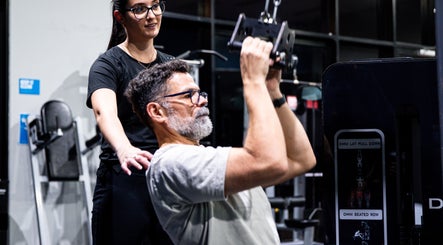 Instructor at LeanFit Performance, Birtinya guides a man using gym equipment.
