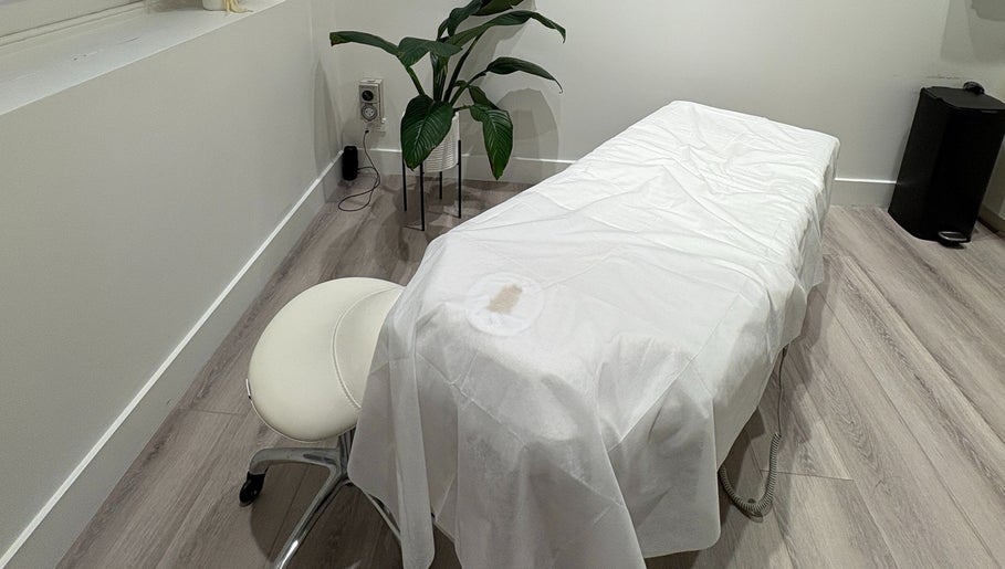 Tranquil massage room at Keenest, Melbourne, Victoria, AU with a white treatment bed and green plant.