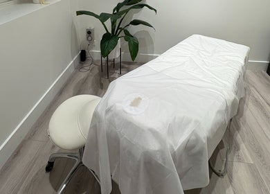 Tranquil massage room at Keenest, Melbourne, Victoria, AU with a white treatment bed and green plant.