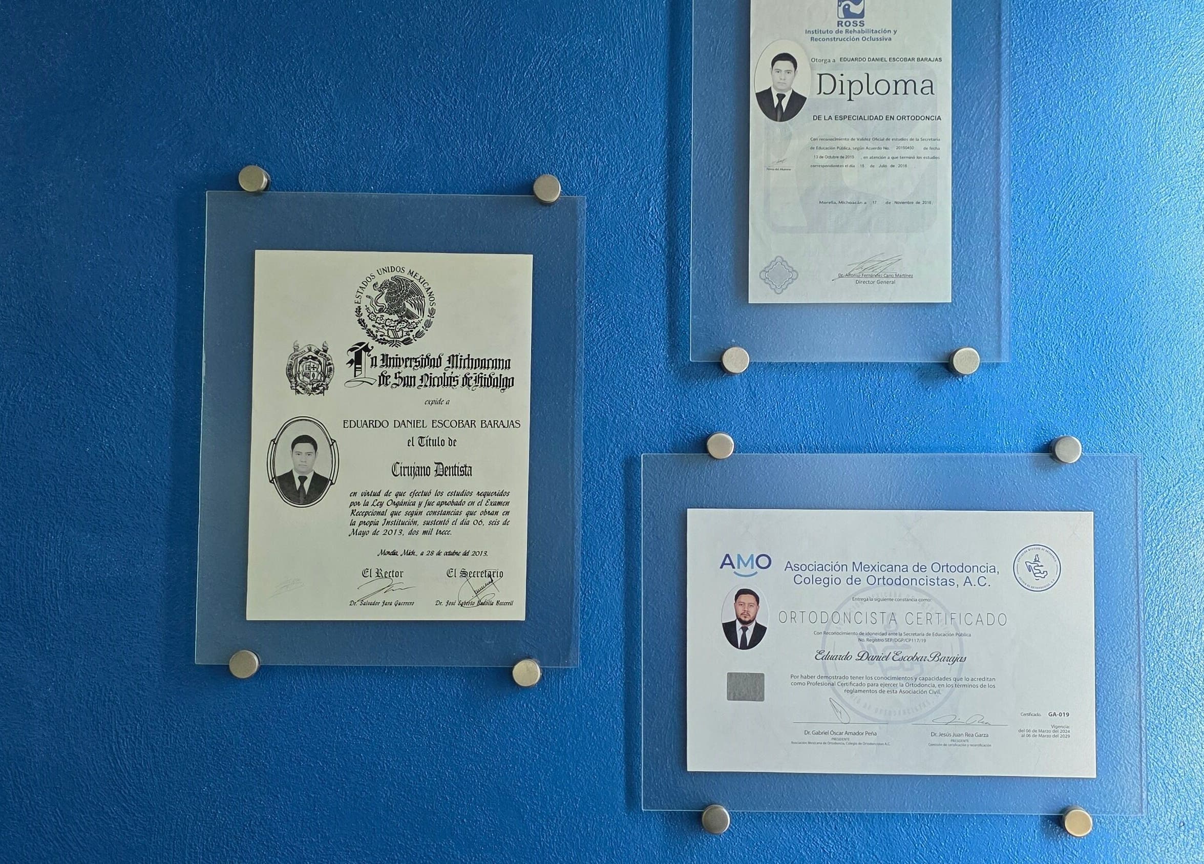 Certificados de Eduardo Escobar Ortodoncia en Los Reyes De Salgado, Michoacán, MX sobre pared azul.