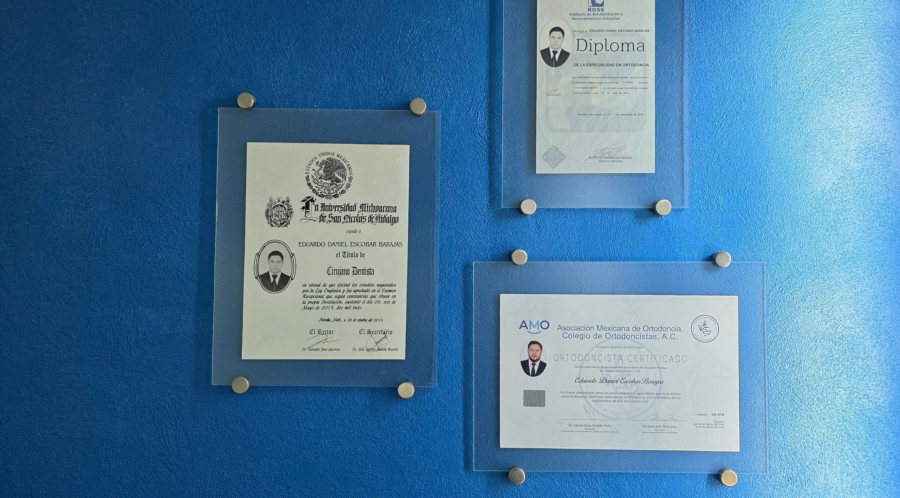 Certificados de Eduardo Escobar Ortodoncia en Los Reyes De Salgado, Michoacán, MX sobre pared azul.