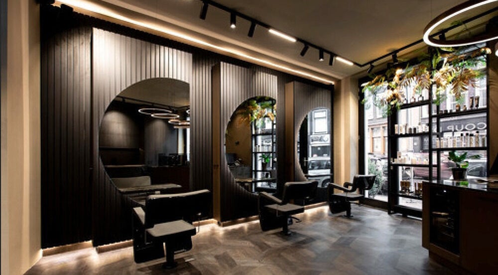 Modern interior of Hairsalon Coup D'état, Amsterdam, NL with sleek styling chairs and elegant decor.