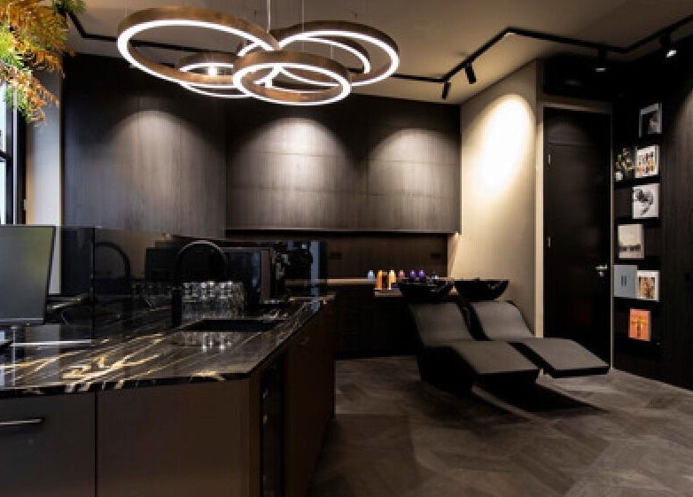 Modern salon interior at Hairsalon Coup D'état, Amsterdam, NL with sleek black design and elegant lighting.