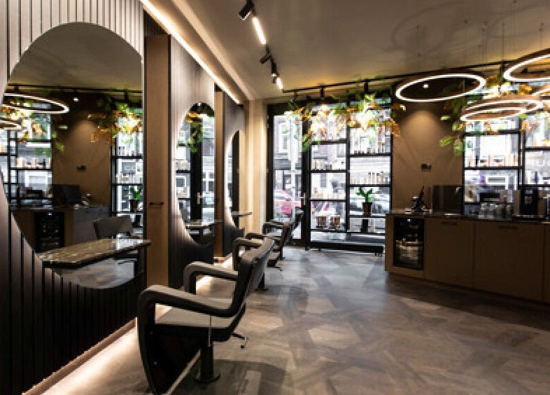 Sleek interior of Hairsalon Coup D'état, Amsterdam, NL with modern seating and large mirrors.