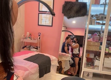 Client receiving lash treatment at Pink Lounge Lash | PMU, Louisville, Kentucky, US in a cozy pink room.