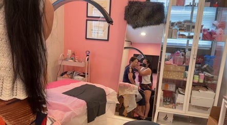 Client receiving lash treatment at Pink Lounge Lash | PMU, Louisville, Kentucky, US in a cozy pink room.