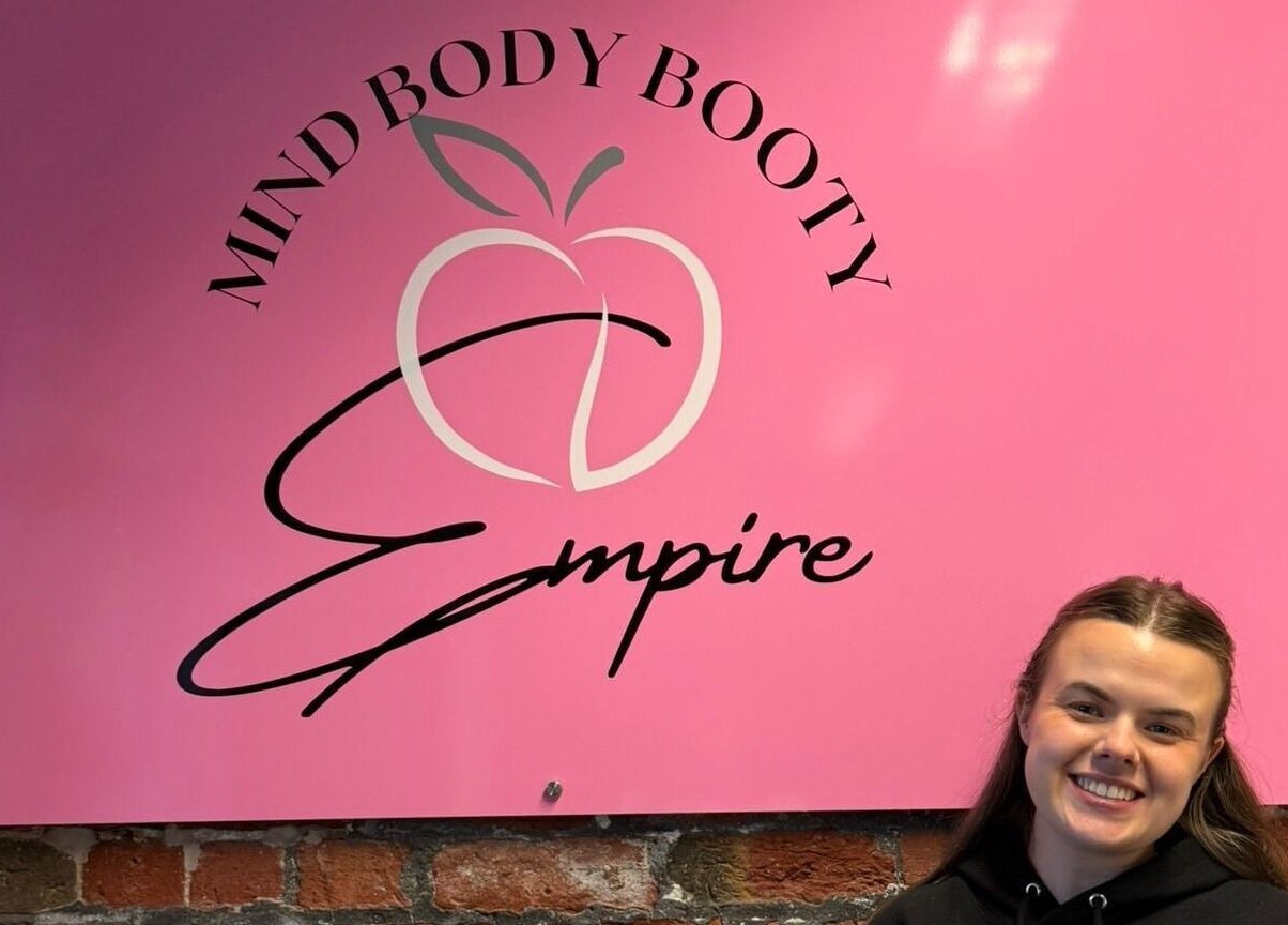 Welcoming pink sign at Hayley's Health Hub in Knowsley, England, GB with smiling woman.