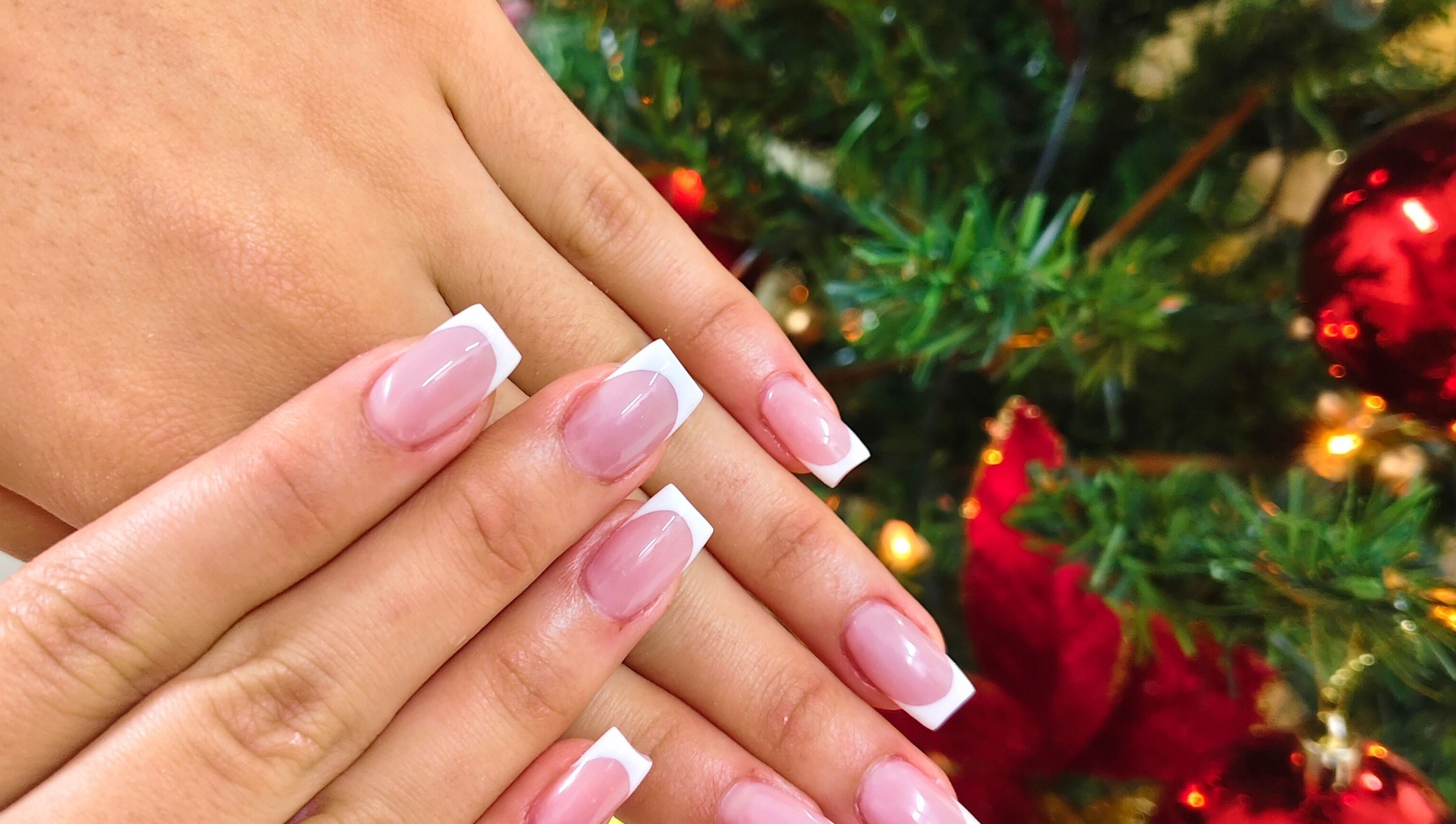 Elegant French manicure at Cosmopolitas Nails & Beauty care, Willemstad, Curaçao, CW, with festive decor.