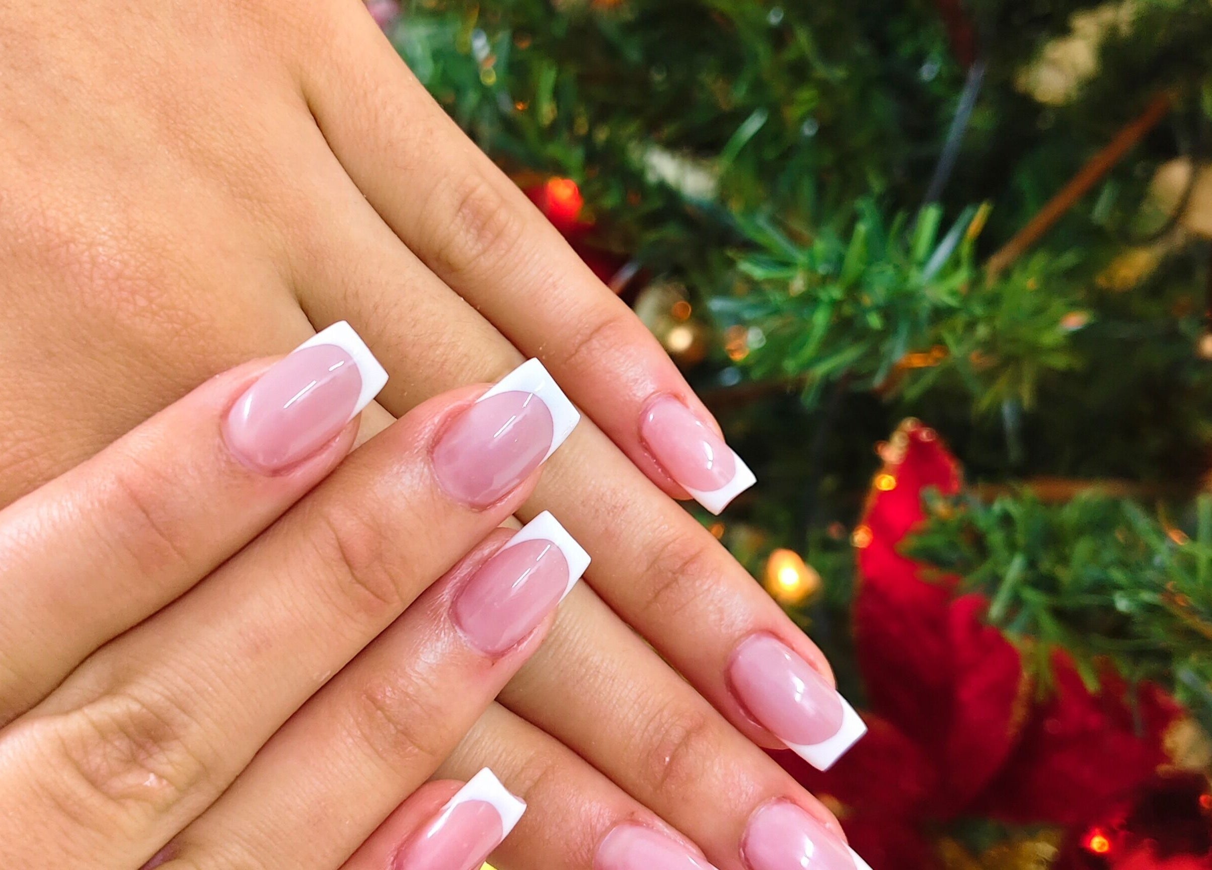 Elegant French manicure at Cosmopolitas Nails & Beauty care, Willemstad, Curaçao, CW, with festive decor.