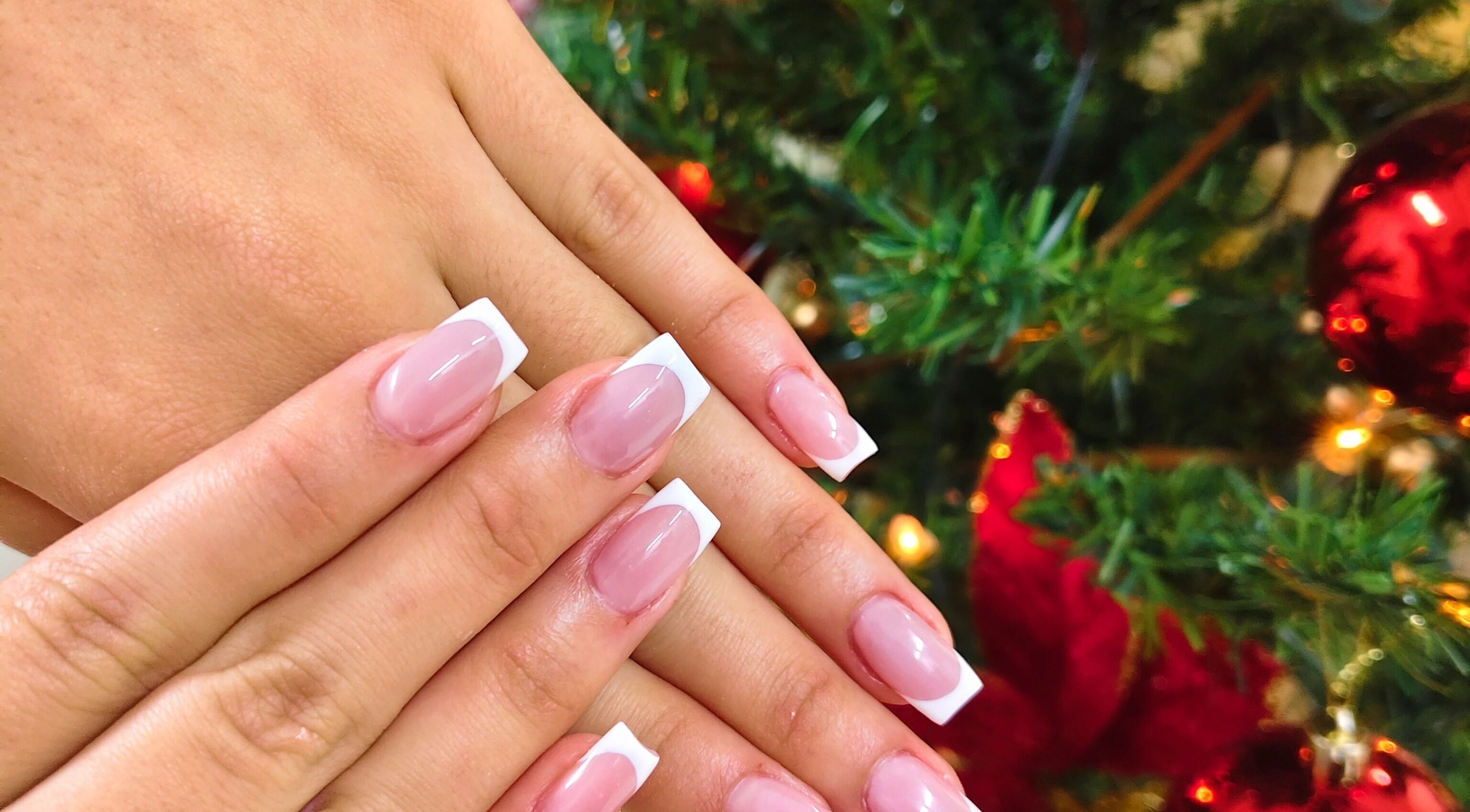 Elegant French manicure at Cosmopolitas Nails & Beauty care, Willemstad, Curaçao, CW, with festive decor.