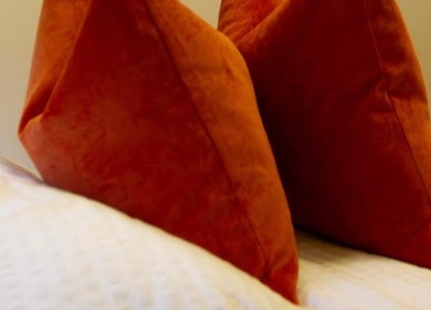 Luxurious orange pillows on a bed at Beauty By Aimee, Dundee, Scotland, GB.
