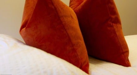 Luxurious orange pillows on a bed at Beauty By Aimee, Dundee, Scotland, GB.