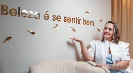 Profissional sorrindo no Guta Maciel, Minas Gerais, BR, com slogan 'Beleza é se sentir bem' na parede.