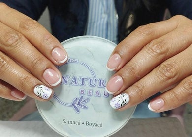 Uñas con diseño floral en Natural Beauty, Samacá, Boyacá, CO, sobre fondo de logotipo.