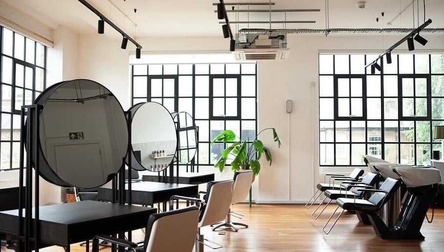 Modern salon interior at Hair By Ashley Rose, London, England, GB featuring sleek styling stations and bright windows.