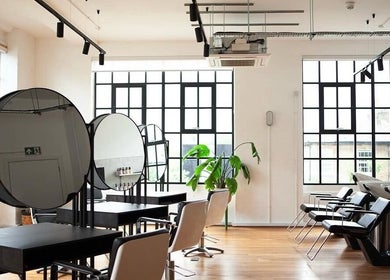 Modern salon interior at Hair By Ashley Rose, London, England, GB featuring sleek styling stations and bright windows.