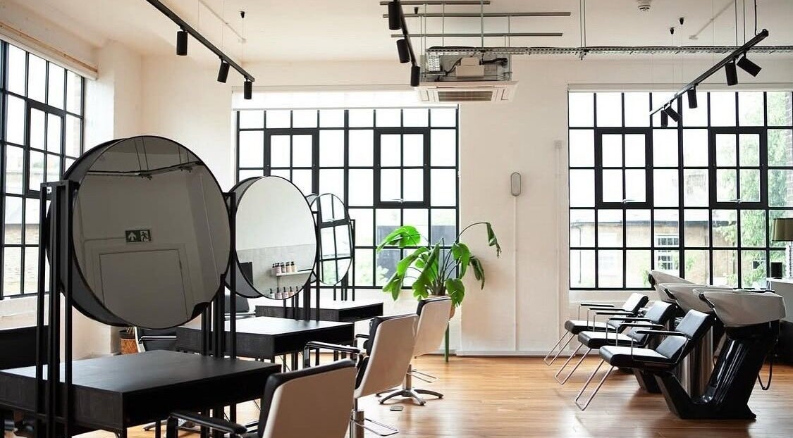 Modern salon interior at Hair By Ashley Rose, London, England, GB featuring sleek styling stations and bright windows.