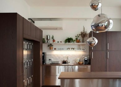 Modern kitchen area at Hair By Ashley Rose, London, England, GB featuring wooden cabinets and sleek countertops.
