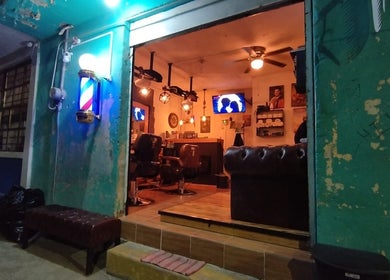 Entrada de HH Altair's Barbershop Reborn en El Cooperativo, Estado De México, MX, iluminada por la noche.