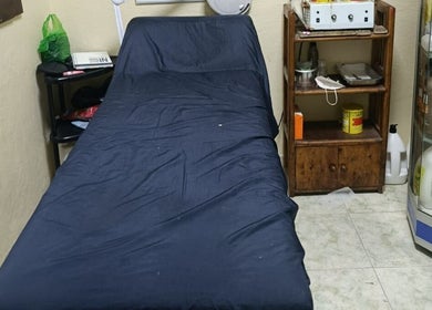 Cama de tratamiento en Alajas Peluquería, Quito, Pichincha, EC, con productos de belleza en estantería.
