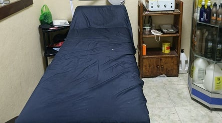 Cama de tratamiento en Alajas Peluquería, Quito, Pichincha, EC, con productos de belleza en estantería.