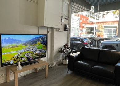 Relaxed seating area at Ocean hair salon design, Melbourne, Victoria, AU, featuring a TV and leather sofa.