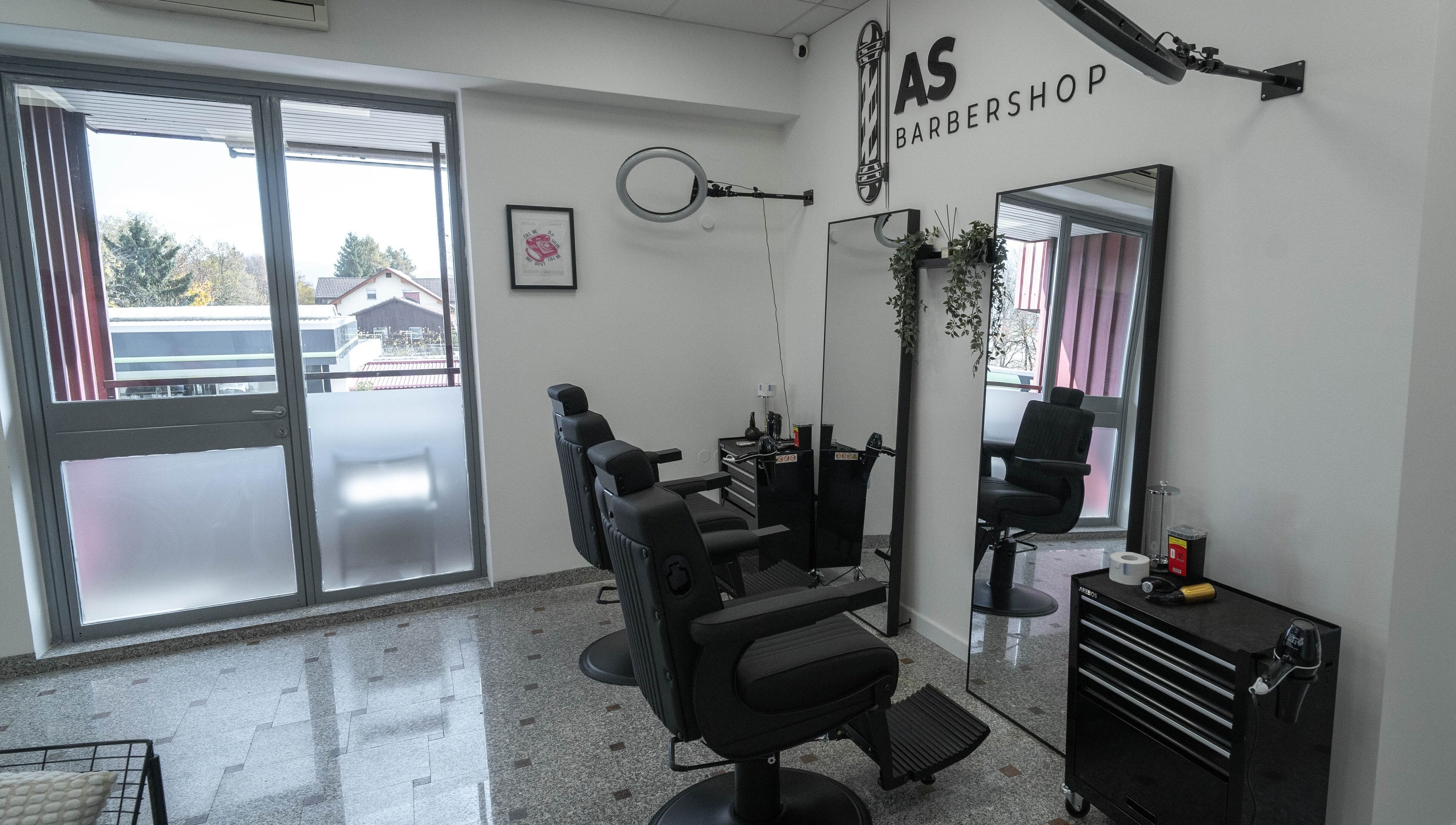 Sodoben prostor AS Barbershop, Ljubljana, Ljubljana, SI z dvema udobnima stoloma in velikim ogledalom.