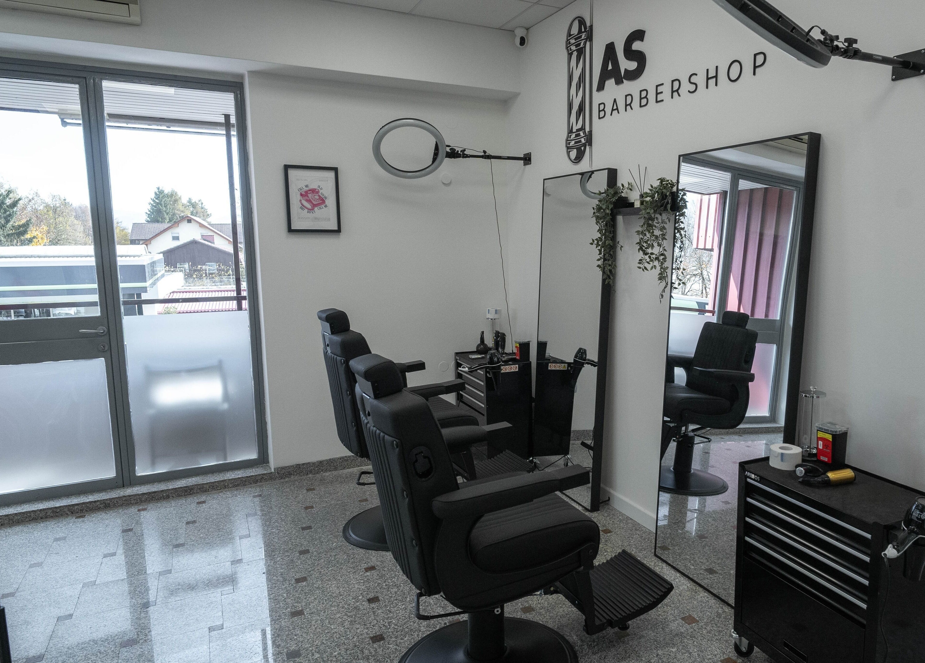 Sodoben prostor AS Barbershop, Ljubljana, Ljubljana, SI z dvema udobnima stoloma in velikim ogledalom.