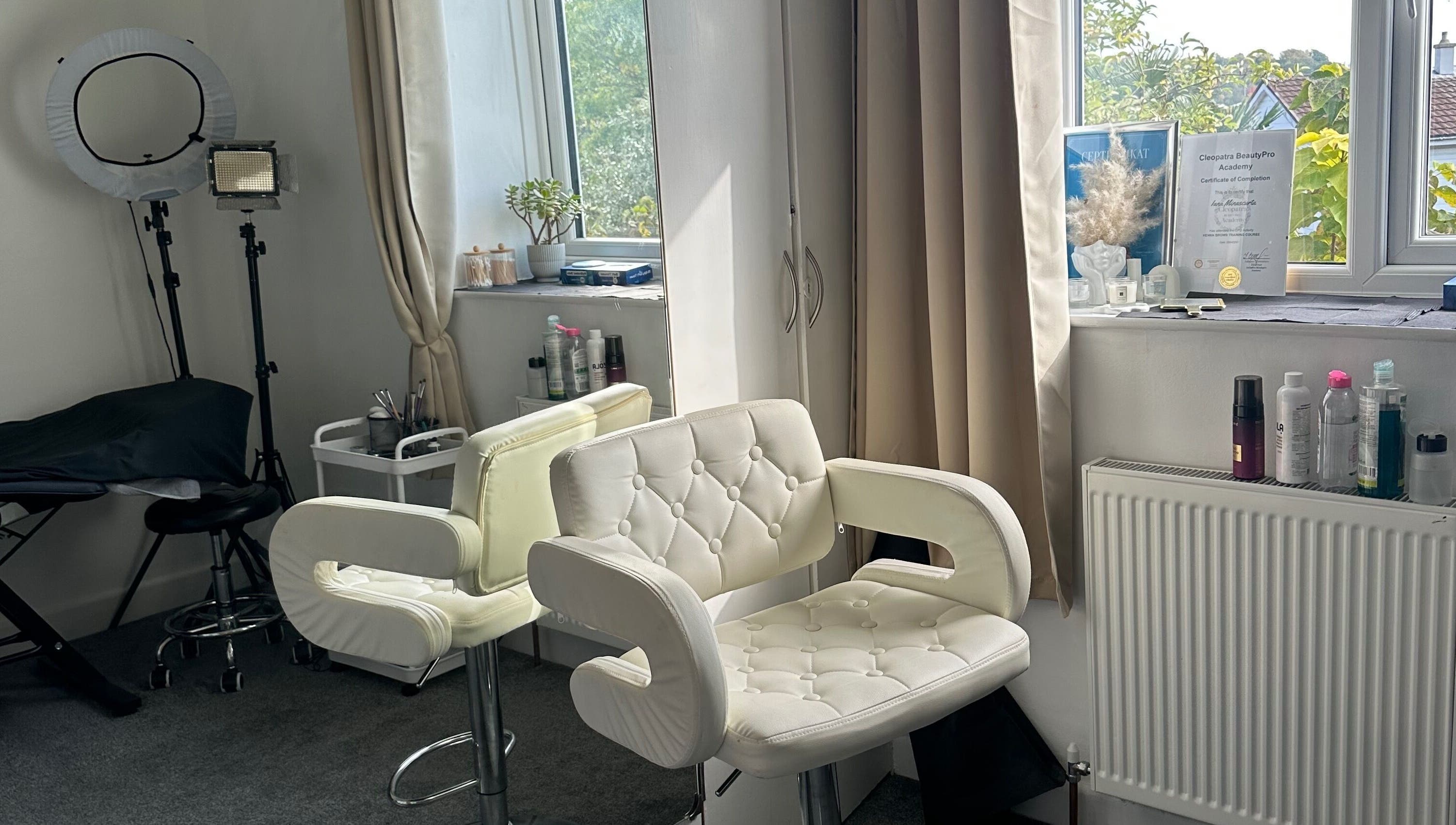 Bright beauty studio at Perfect Brows, Ilford, England, GB with stylish white chairs and beauty tools.