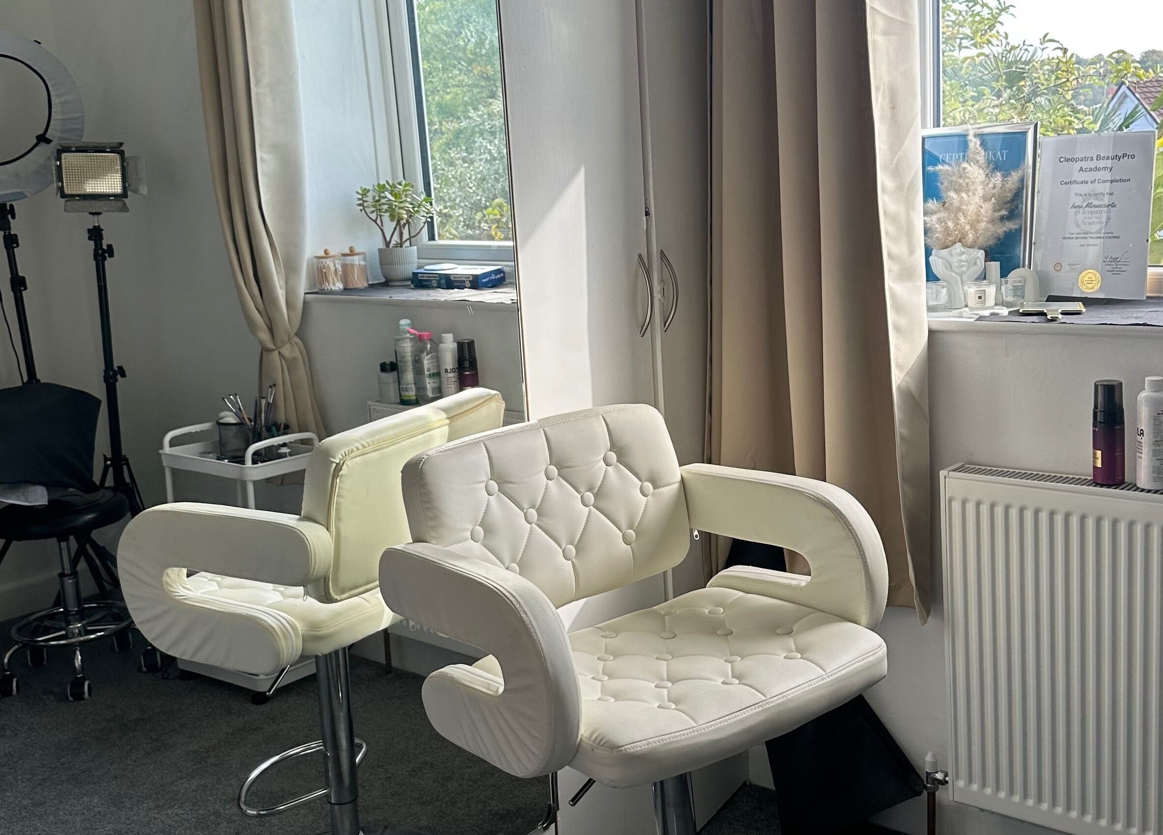 Bright beauty studio at Perfect Brows, Ilford, England, GB with stylish white chairs and beauty tools.