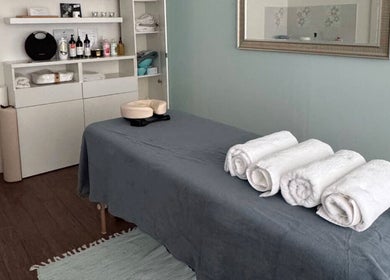 Masážní místnost v BodyCare Prague, Hlavní Město Praha, CZ s šedým prostěradlem a bílými ručníky.