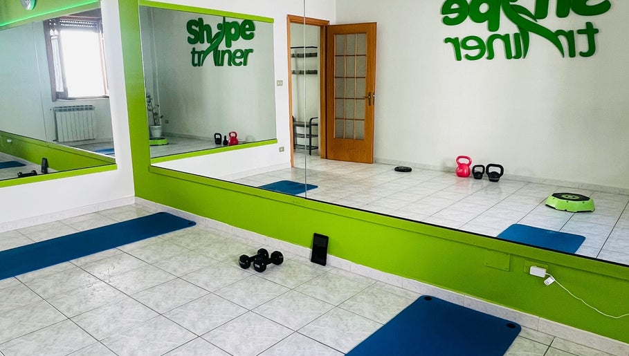 Interno della palestra Shape Trainer con specchi e attrezzi a Messina, Sicilia, IT.