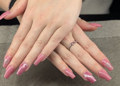 Glamorous pink manicured nails at Starz & Knyvz Nails, Beaconsfield, England, GB on textured mat.
