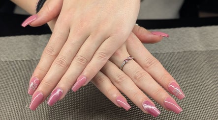 Glamorous pink manicured nails at Starz & Knyvz Nails, Beaconsfield, England, GB on textured mat.