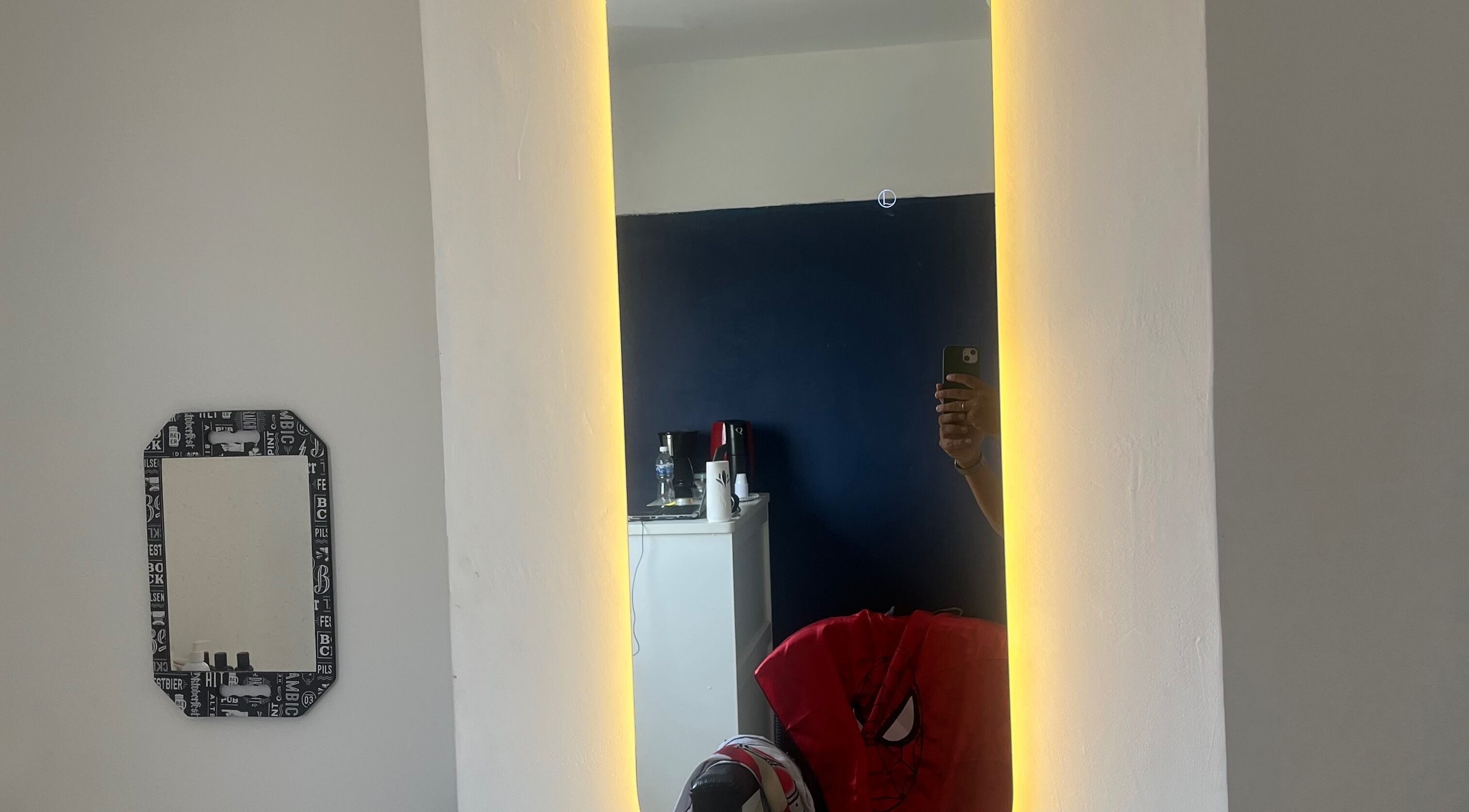 Espelho iluminado na RaphabarberShop em Maranhão, Maranhão, BR, refletindo parte de um interior moderno.