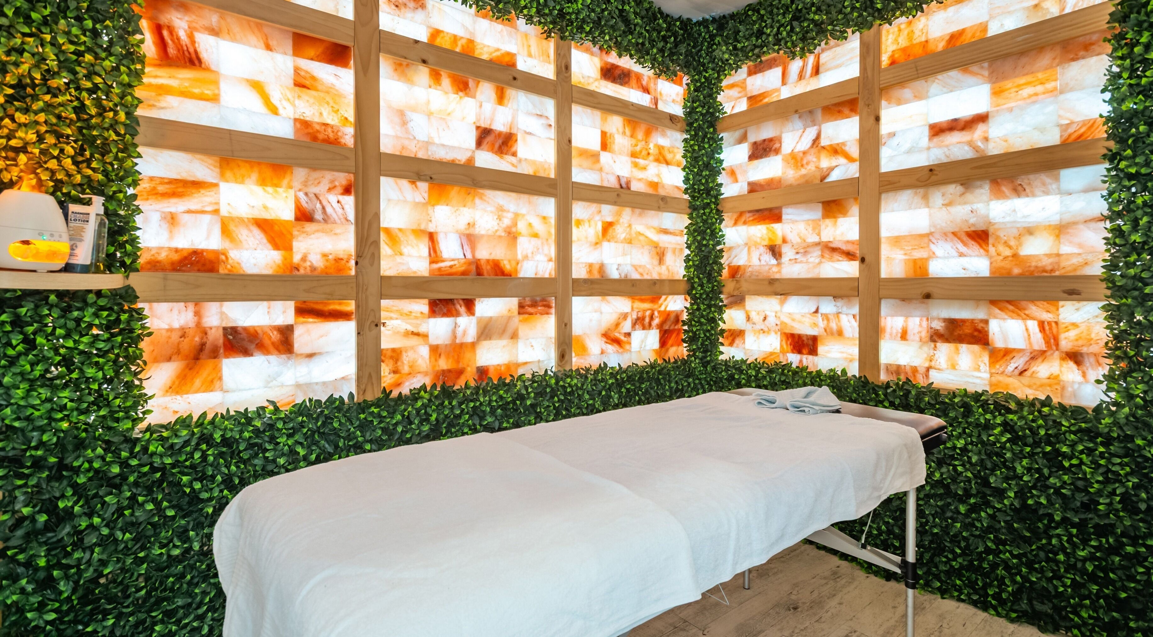 Tranquil massage room at Halo Sanctuary in Ramsgate, New South Wales, AU with Himalayan salt wall and greenery.