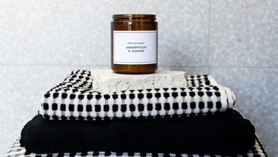 Amberwood & Jasmine candle on towels at Palm Beach Glow, Palm Beach, Queensland, AU.