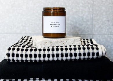 Amberwood & Jasmine candle on towels at Palm Beach Glow, Palm Beach, Queensland, AU.
