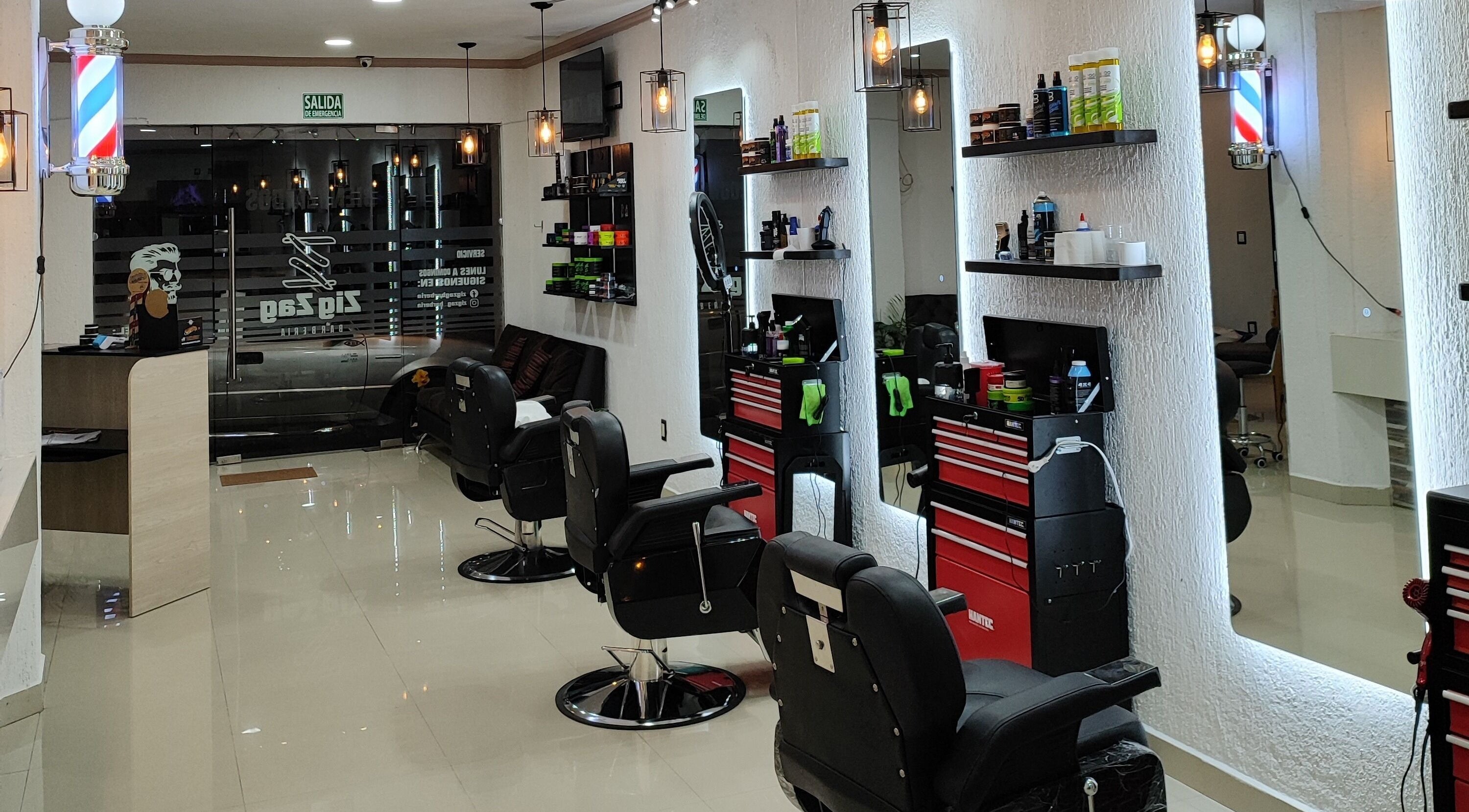 Interior moderno de ZigZag Barbería en San Cristóbal De Las Casas, Chiapas, MX con elegantes sillas y espejos iluminados.